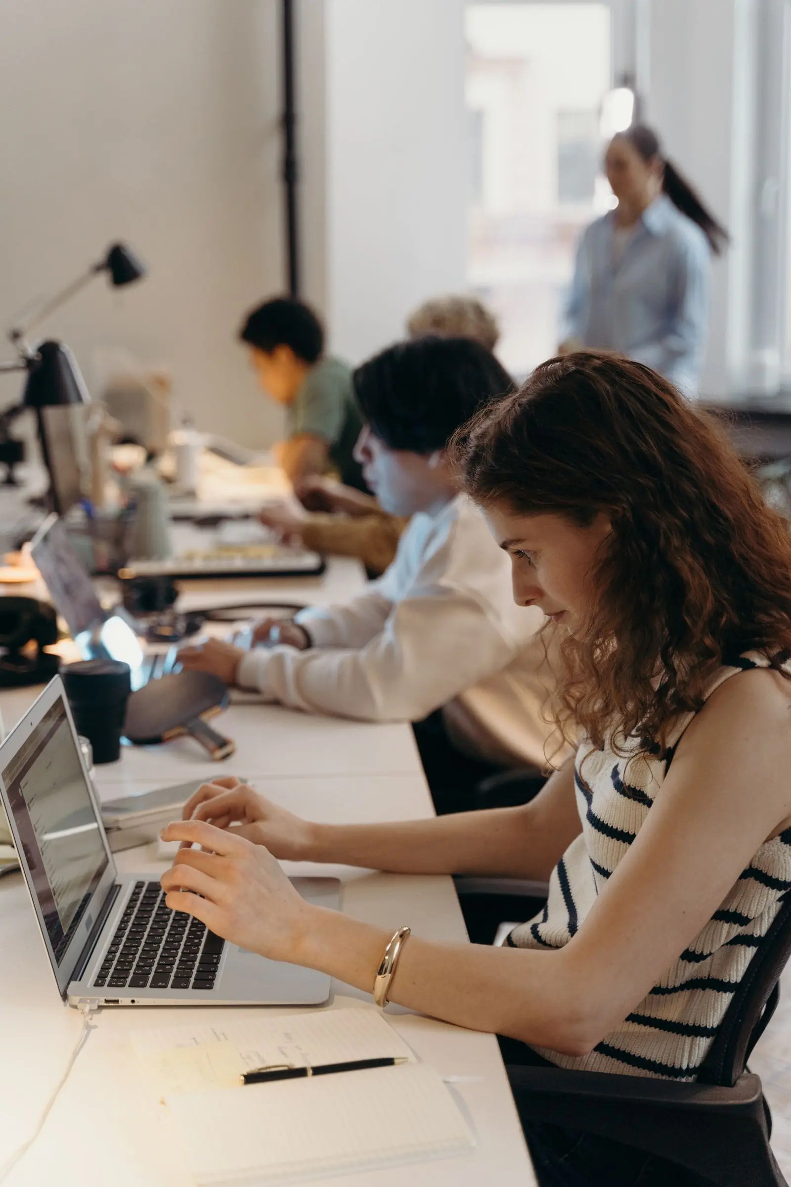 People working on laptops at a shared studio desk